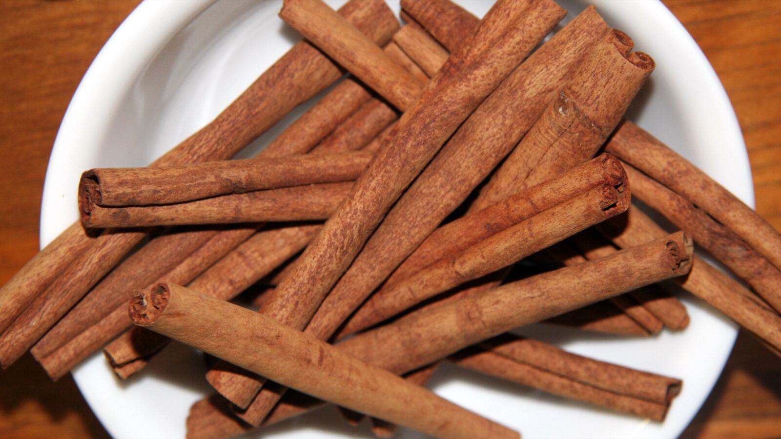 Cinnamon quills of rolled dried bark beside cinnamon tree foliage